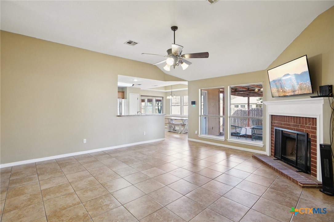 7114 Pappus Court Temple, TX 76502 - Photo 4 of 28 a view of a livingroom with a fireplace a chandelier fan and windows
