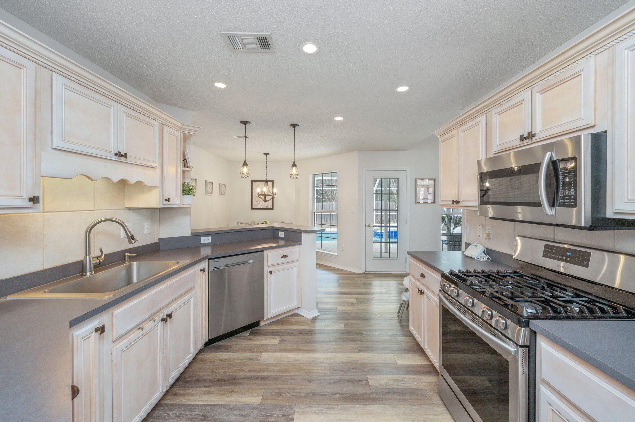 730 Denise Drive Crestview, FL 32536 - Photo 11 of 40 a large kitchen with stainless steel appliances granite countertop a lot of counter space a sink and dishwasher a stove top oven with wooden floor