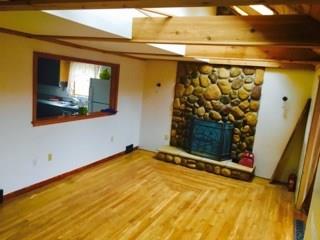 524 Friel Road Baden, PA 15005 - Photo 2 of 25 Living room with fabulous stone fireplace, beautiful hardwood floors and wood beamed vaulted ceiling with sky lights! Opening to kitchen located on the left.