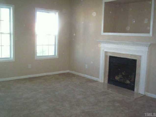 6811 Spanglers Spring Way Raleigh, NC 27610 - Photo 3 of 7 an empty room with a fireplace and windows