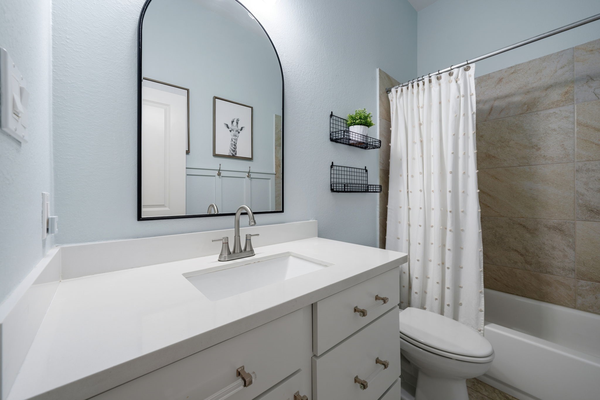 2119 Blackhawk Ridge Lane Manvel, TX 77578 - Photo 30 of 49 Secondary Bathroom (Boy's/Hall Bath)
Clean and stylish secondary bathroom with brushed nickel fixtures, arched framed mirror, and a tiled tub/shower combo — tastefully decorated with modern charm.