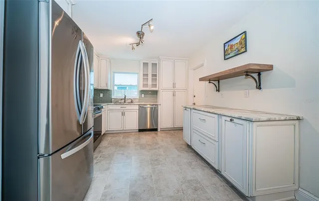a kitchen with granite countertop stainless steel appliances and refrigerator