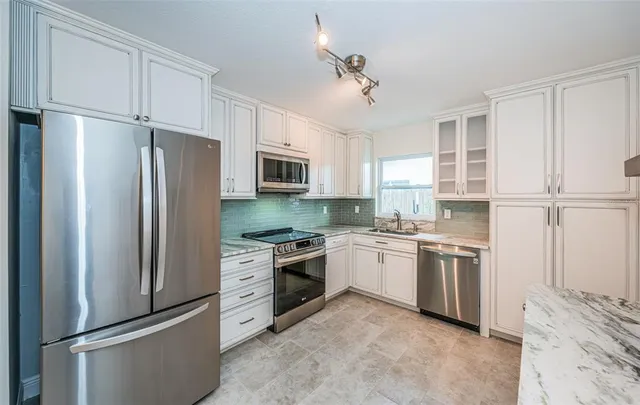 a kitchen with white cabinets stainless steel appliances and sink