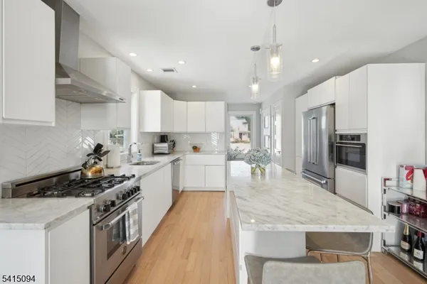 a kitchen with kitchen island a counter top space a sink stainless steel appliances and cabinets