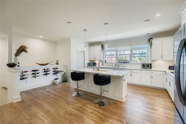 a kitchen with a refrigerator a stove top oven a sink dishwasher and white cabinets with wooden floor