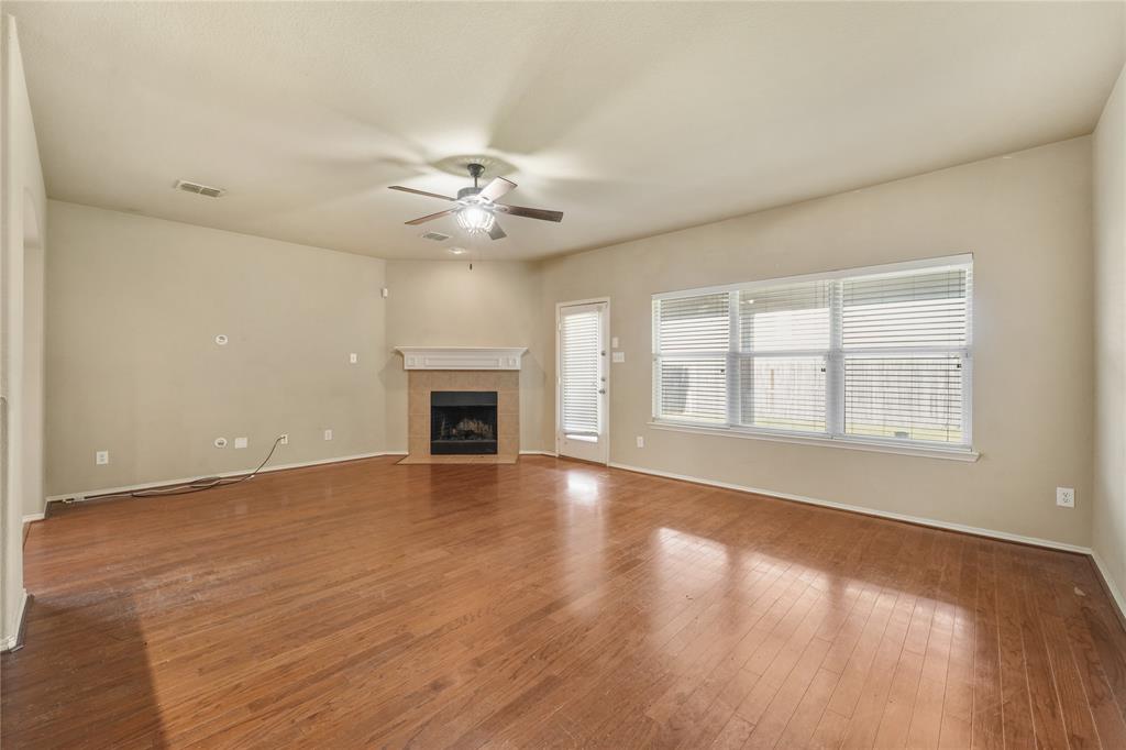 2003 Diamondback Forney, TX 75126 - Photo 7 of 30 Unfurnished living room featuring plenty of natural light, ceiling fan, hardwood / wood-style flooring, and a tiled fireplace