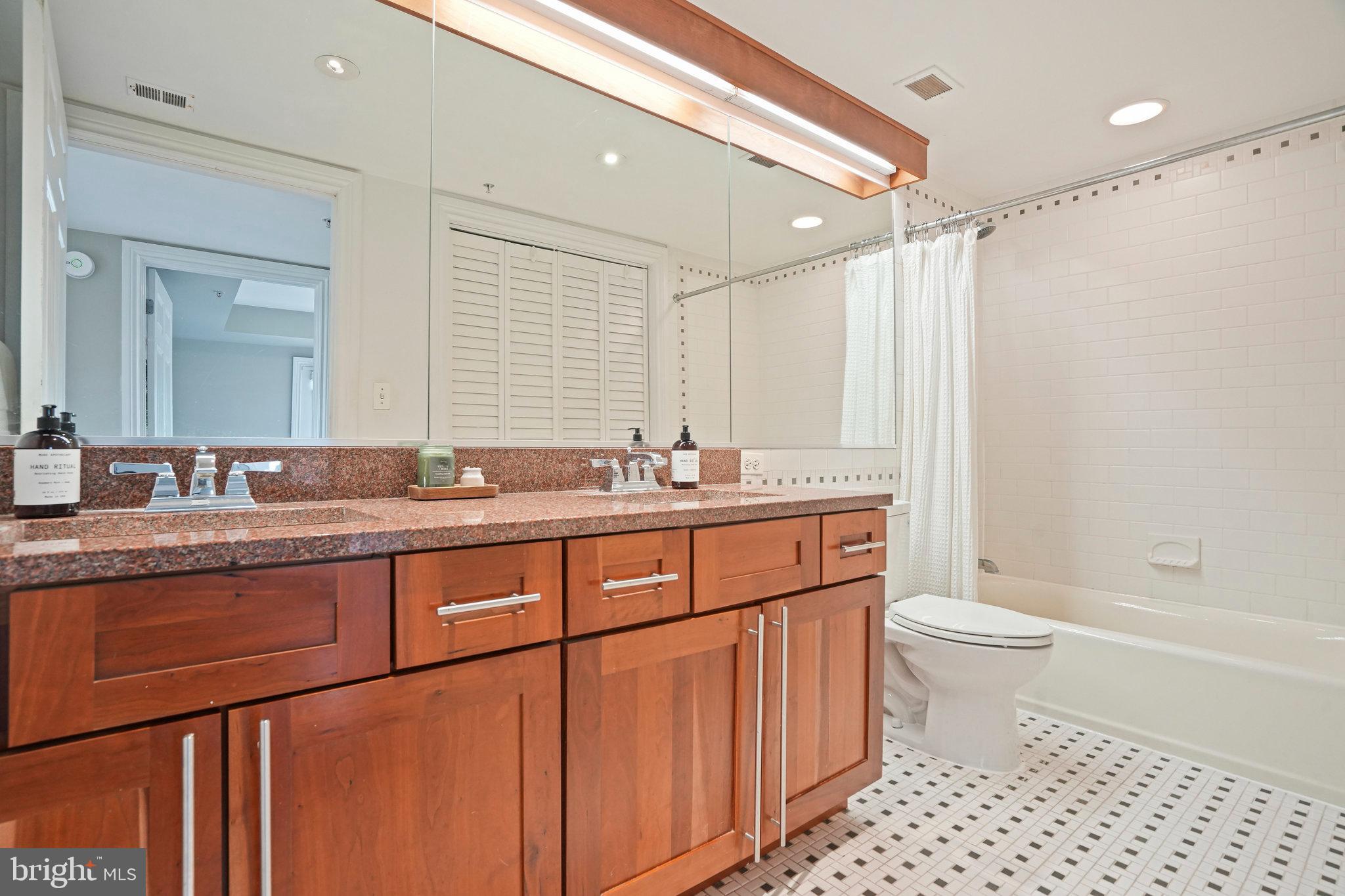 1020 Pennsylvania Ave. Southeast, Unit 404 Washington, DC 20003 - Photo 19 of 24 a bathroom with a granite countertop sink a toilet a shower and a mirror