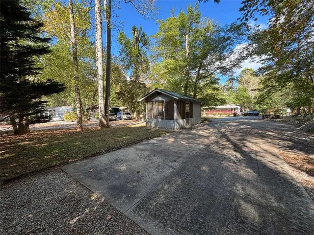 a backyard of a house with large trees and wooden fence