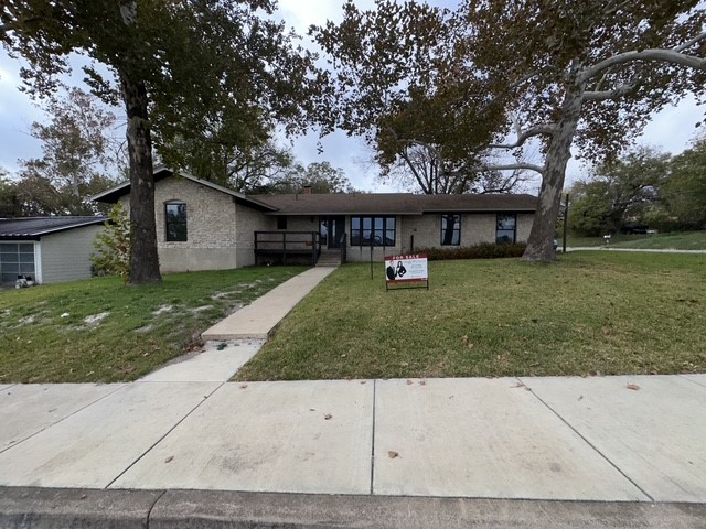 Ranch-style home with a front yard and brick siding