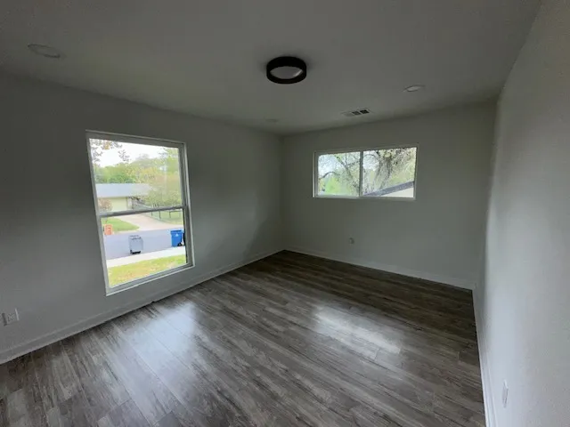 an empty room with wooden floor and windows