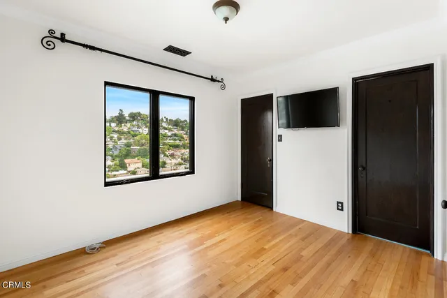 a view of an empty room with wooden floor and a window
