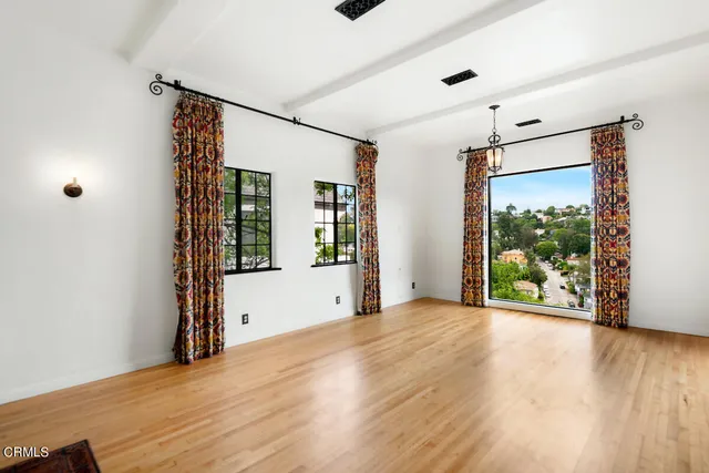 a view of an empty room with wooden floor and a window