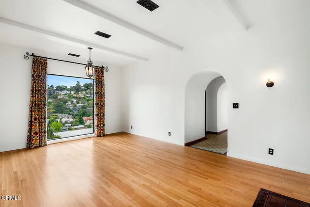a view of an empty room with wooden floor and a window
