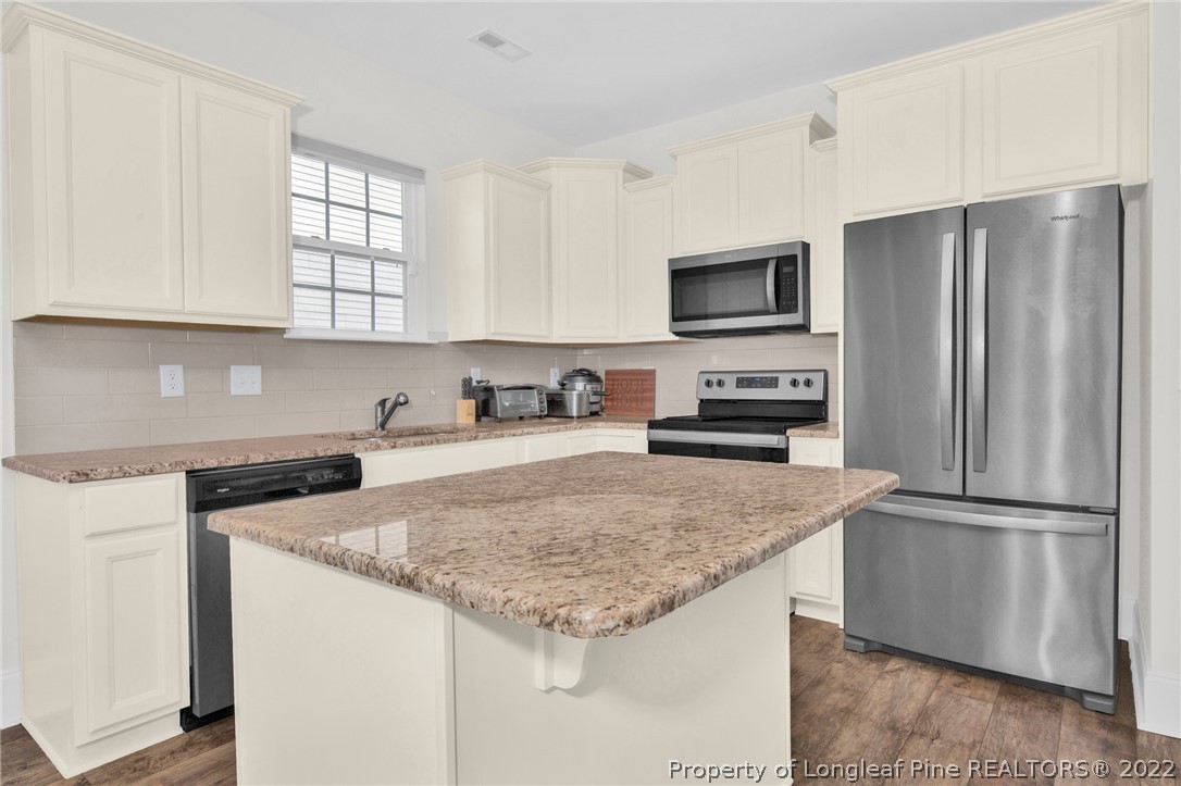 126 Verdmont Drive Raeford, NC 28376 - Photo 11 of 30 a kitchen with granite countertop a refrigerator and a stove top oven