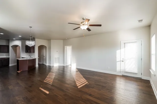 a view of an empty room with window and wooden floor