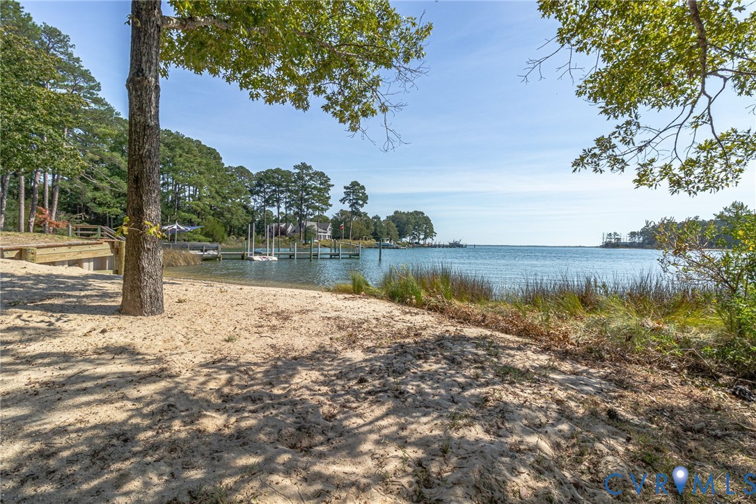 Sandy beach area with mature trees, dock, and a pr