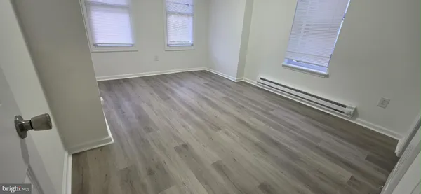 a view of an empty room with wooden floor and entryway