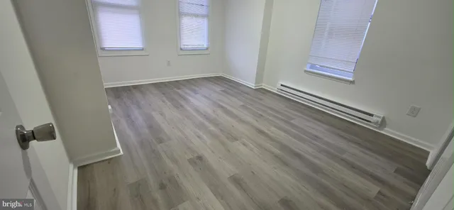 a view of an empty room with wooden floor and entryway