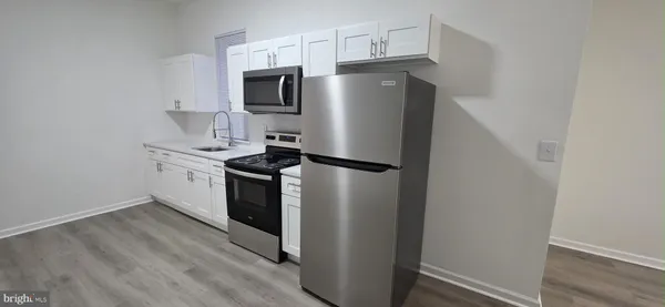 a kitchen with stainless steel appliances a refrigerator a sink and white cabinets
