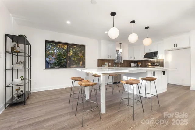 a kitchen with stainless steel appliances kitchen island granite countertop a stove a sink dishwasher and white cabinets with wooden floor