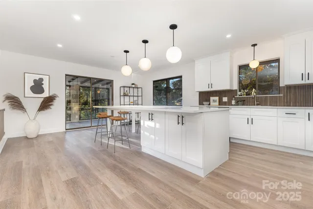 a large white kitchen with lots of counter space cabinets and appliances