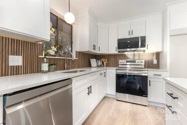 a kitchen with stainless steel appliances white cabinets a sink and a stove