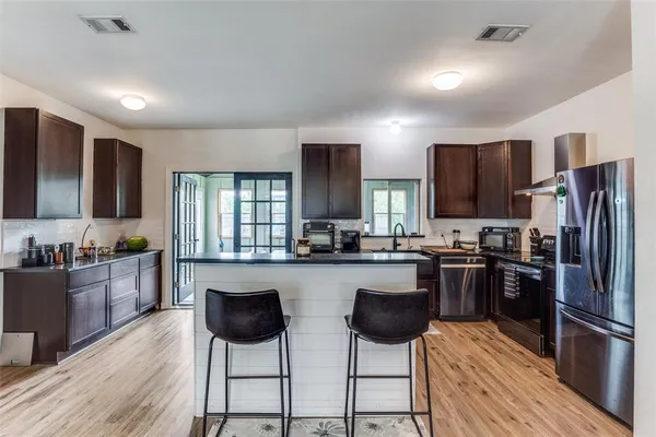 a kitchen with stainless steel appliances kitchen island granite countertop a stove refrigerator and cabinets