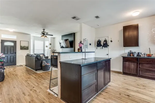 a kitchen with stainless steel appliances kitchen island granite countertop a sink counter space and a view of living room