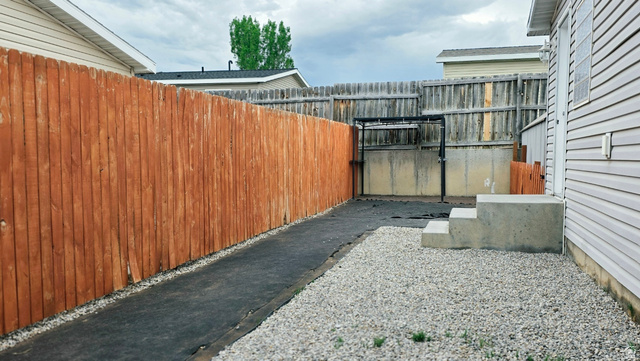 401 West 2000th Street South Vernal, UT 84078 - Photo 23 of 26 Backyard area featuring a newly stained wood fence, concrete steps, and a gravel-covered ground surface