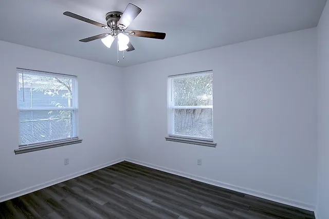 a view of an empty room with a window and wooden floor