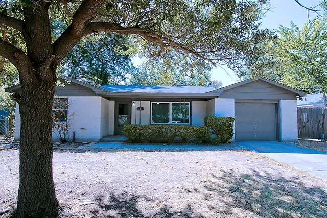 a view of a house with a yard and large trees
