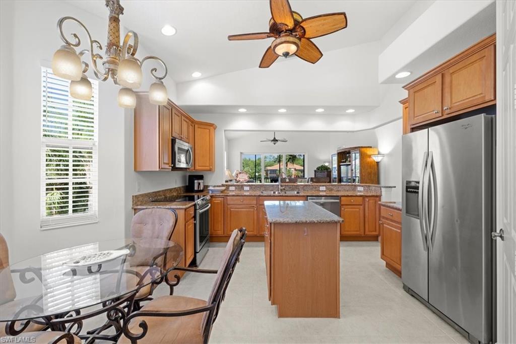6443 Legacy Circle, Unit 1103 Naples, FL 34113 - Photo 12 of 35 a kitchen with stainless steel appliances granite countertop a refrigerator a sink dishwasher a dining table and chairs with wooden floor