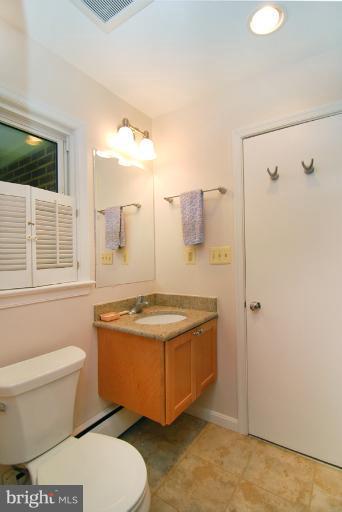 6425 Lignum Street Springfield, VA 22150 - Photo 4 of 30 a bathroom with a granite countertop toilet a sink and a window