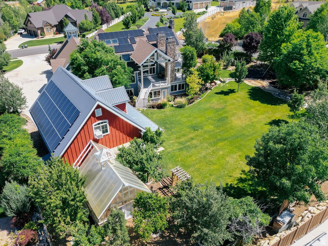 672 Perry Hollow Drive Mapleton, UT 84664 - Photo 17 of 106 Expansive grounds featuring a large green lawn, mature trees, and a detached red outbuilding with a metal roof and solar panels