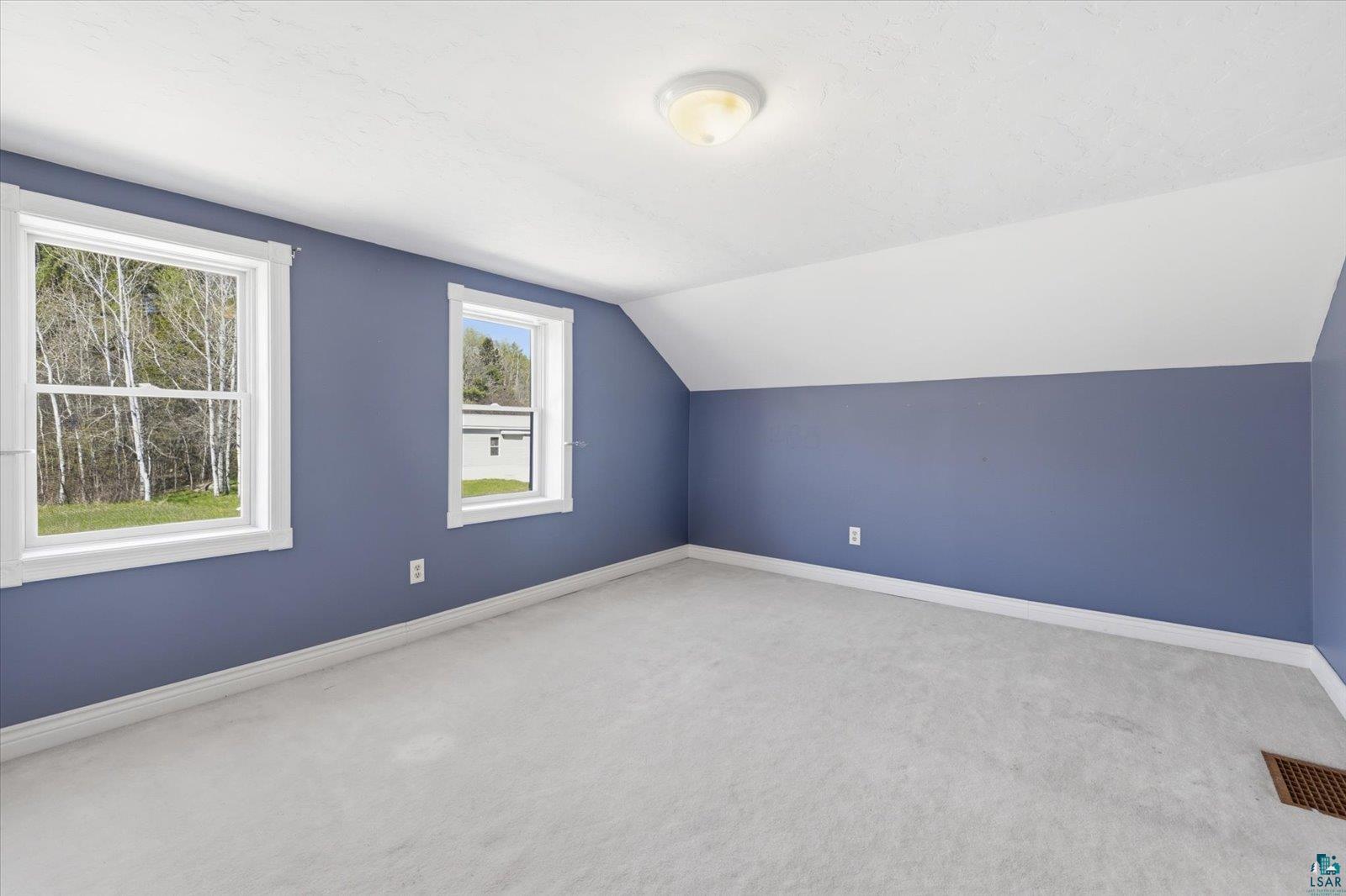 50 Main Street Soudan, MN 55782 - Photo 20 of 31 Spacious room featuring light gray carpeting, two large windows with white trim, and a sloped ceiling