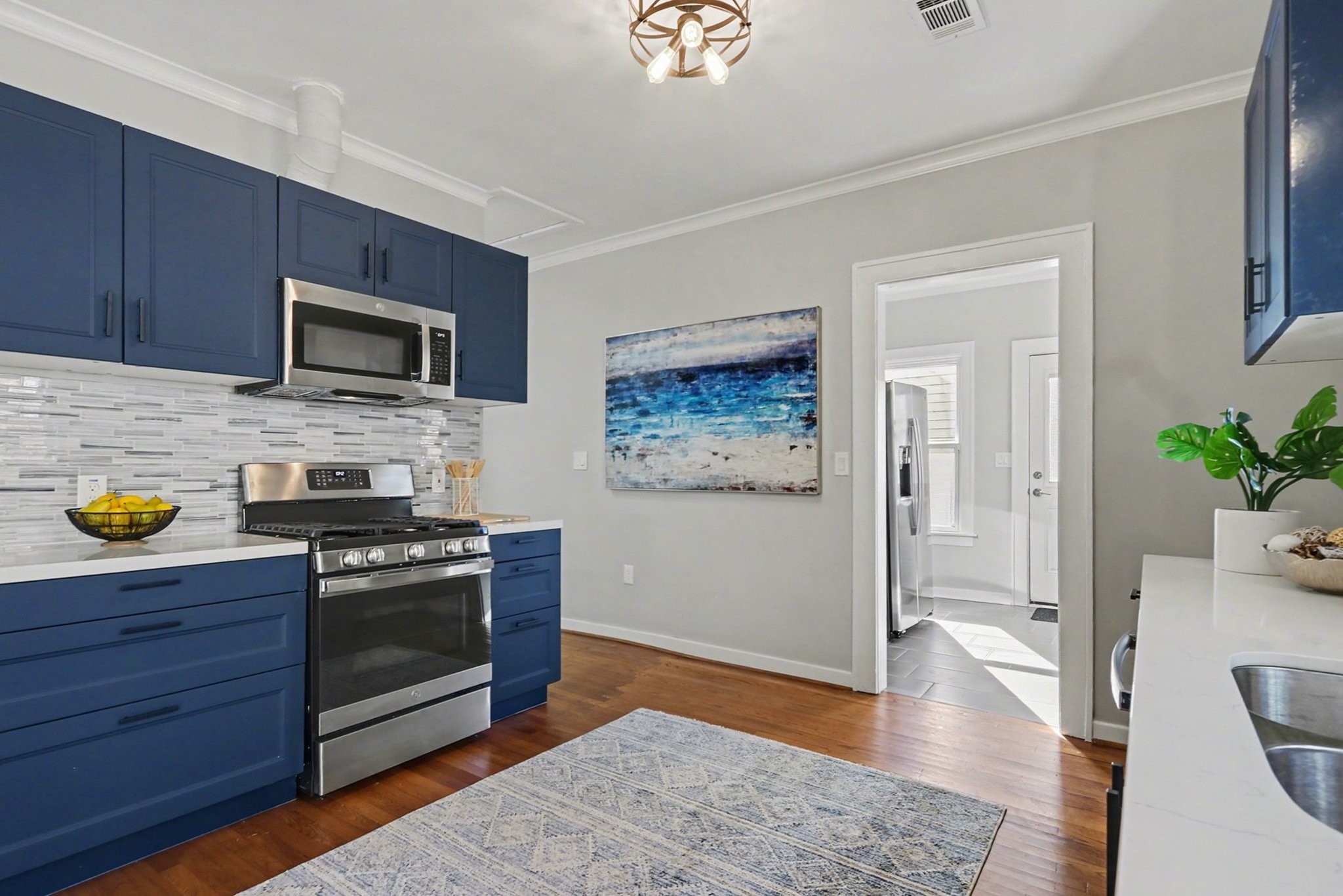 1901 Lexington Street Houston, TX 77098 - Photo 14 of 32 The heart of this home is this exquisite kitchen that seamlessly connects to a utility room with pantry. The hallway to the left of the blue cabinetry leads you to the private primary suite.