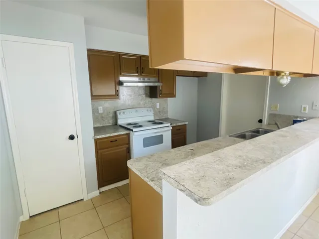 a kitchen with granite countertop a sink a stove and refrigerator