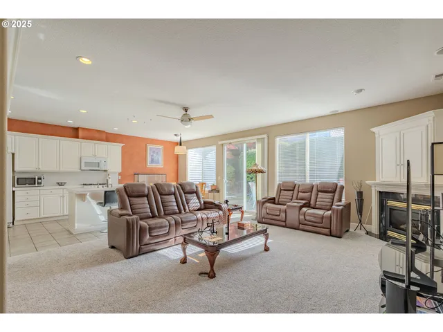 a living room with furniture kitchen view and a large window
