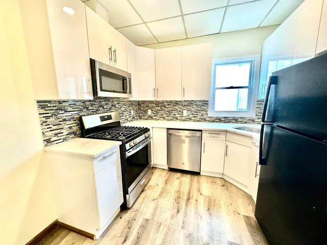 a kitchen with stainless steel appliances a sink cabinets and a wooden floor