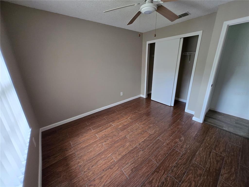 7607 Benji Ridge Trail Kissimmee, FL 34747 - Photo 13 of 58 an empty room with wooden floor and ceiling fan