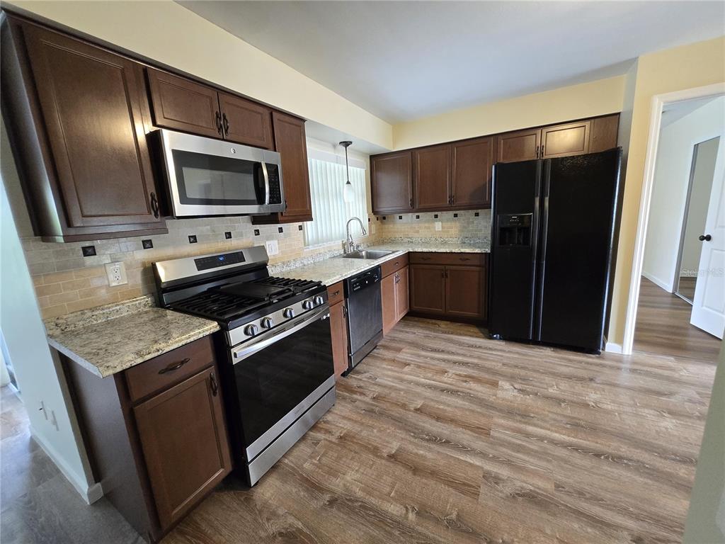 7607 Benji Ridge Trail Kissimmee, FL 34747 - Photo 18 of 58 a kitchen with stainless steel appliances granite countertop a stove a sink and a microwave
