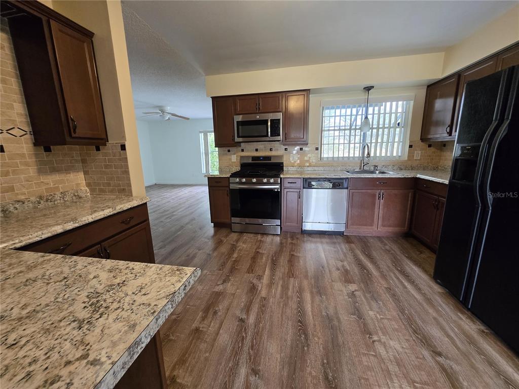7607 Benji Ridge Trail Kissimmee, FL 34747 - Photo 22 of 58 a kitchen with stainless steel appliances granite countertop a stove a sink and a microwave