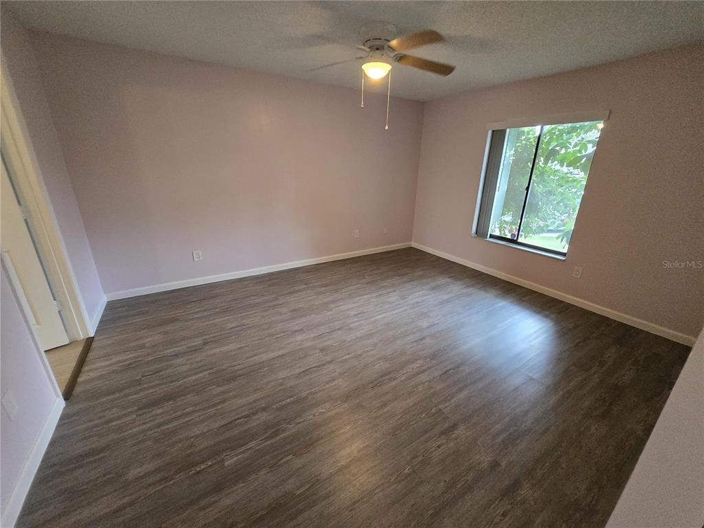 7607 Benji Ridge Trail Kissimmee, FL 34747 - Photo 35 of 58 an empty room with wooden floor fan and windows