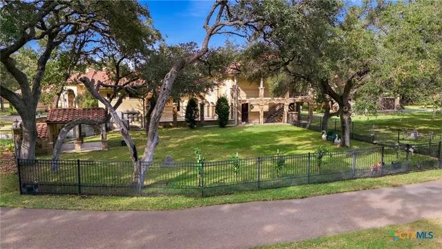 a view of a house with large trees next to a road