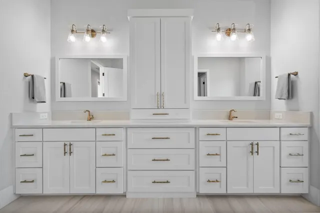 a bathroom with white cabinets and sink