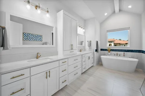 a bathroom with a double vanity sink a large mirror and a bathtub