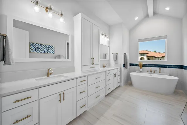 a bathroom with a double vanity sink a large mirror and a bathtub
