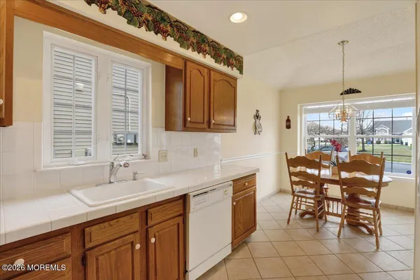 a dining hall with stainless steel appliances a sink dishwasher and cabinets with wooden floor