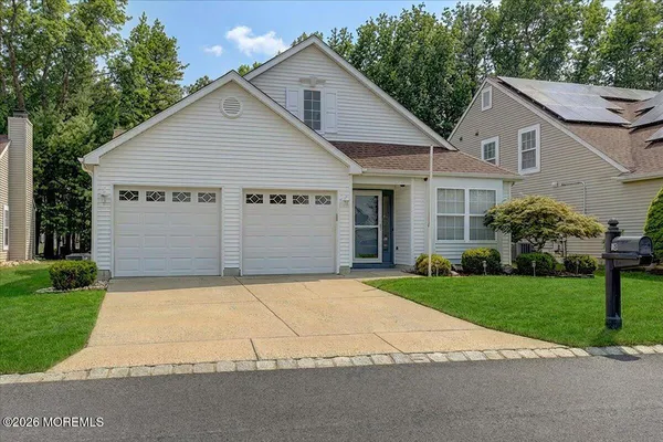 a view of a white house next to a yard and a large tree