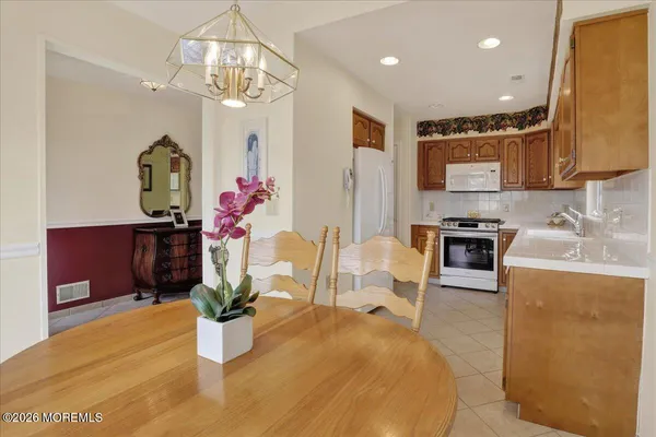 a dining room with wooden floor a chandelier a wooden table and chairs
